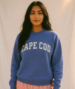 Young smiling woman wearing a periwinkel sweatshirt with the text "Cape Cod" on it