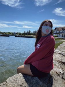 Model sitting by water with Cape Cod product