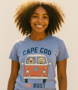 young smiling woman wearing a periwinkel short sleeve tee shirt with an illustration of the front of a bus with the text Cape Cod or Bust