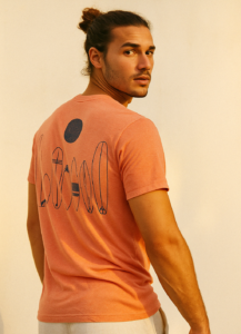 young man wearing a melon short sleeve tee shirt with illustrations of surf boards on it