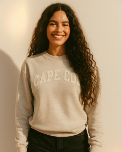 Young smiling woman wearing a light tan sweatshirt with the text "Cape Cod" on it